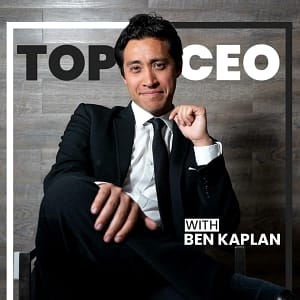 Man in a suit smiling at camera with text overlay "Top CEO Podcasts with Ben Kaplan" against a wooden background.