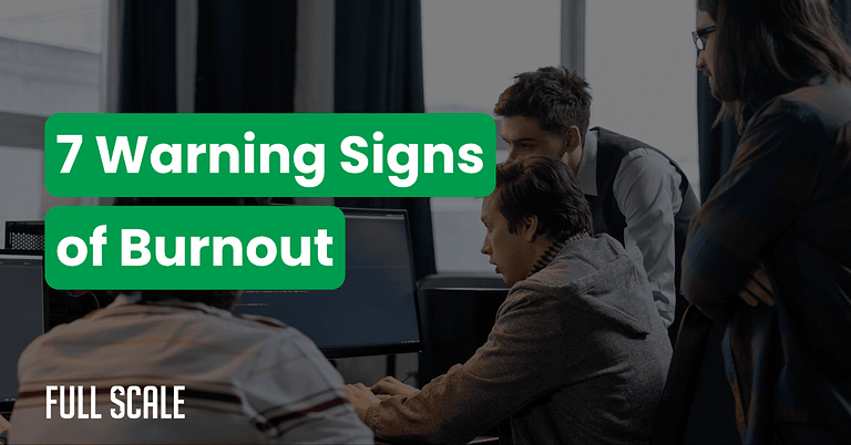 Four people work at computers in an office. Overlaid text reads, "7 Warning Signs of Burnout." The bottom left corner shows the logo "FULL SCALE." Learn key strategies for preventing burnout in development teams.