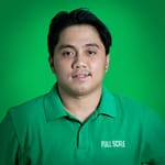 Man with black hair wearing a green collared shirt that says "Paul Sculc," posing in front of a green background.