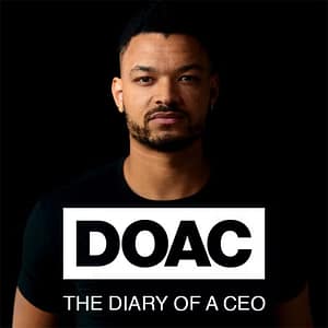 Man with a light beard looking directly at the camera, wearing a black t-shirt with "doac the diary of a ceo podcasts" text in white. Black background.