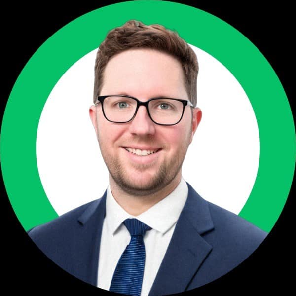 Portrait of a man with short hair and glasses, wearing a suit and tie, with a green circle background.