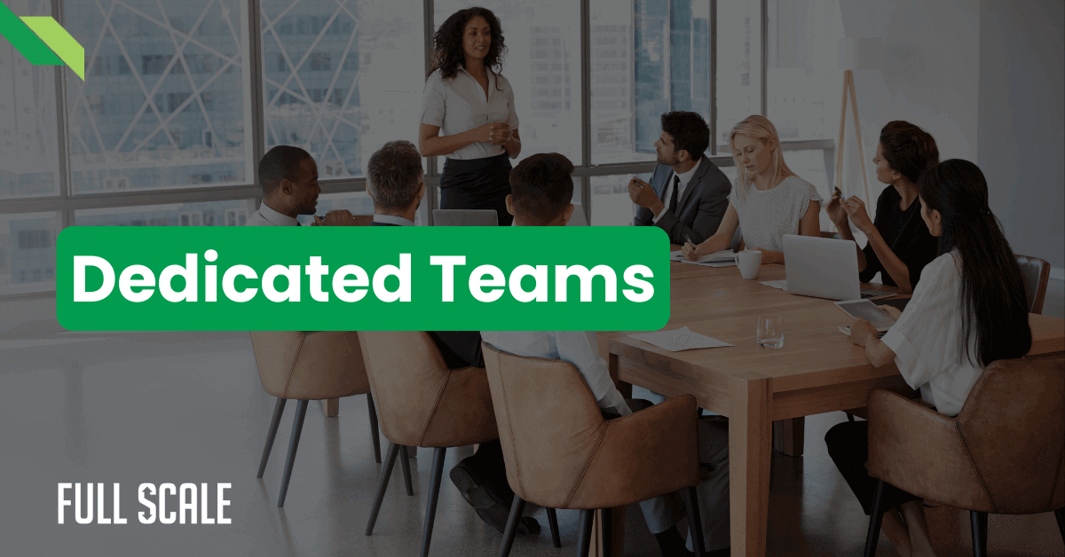 A group of people seated around a conference table, attentively listening to a standing speaker. The text "Dedicated Teams" is prominently displayed in green on the image. "Full Scale" is written at the bottom left.